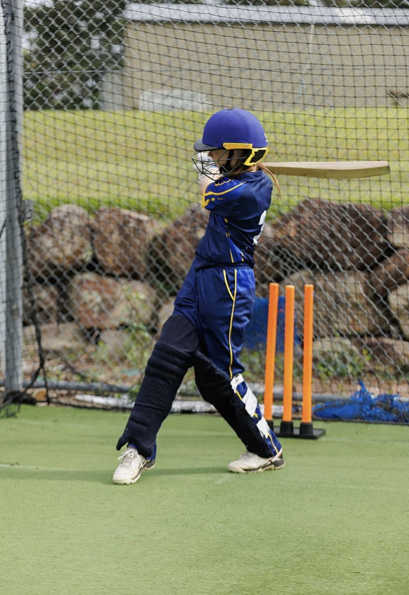 Coach guiding a young cricketer through batting technique adjustments.